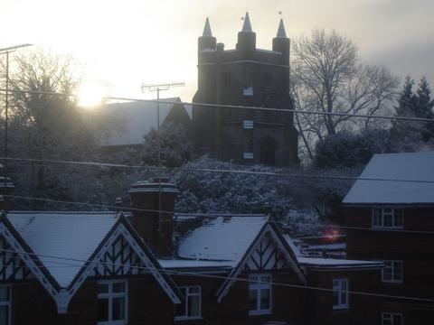 Sun Coming Up Behind The Church In Snow - The winter sun rises behind the church on a snowy morning.