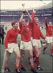 Charlton holds aloft the World Cup 1966 - Sir Robert "Bobby" Charlton, CBE (born 11 October 1937 in Ashington, Northumberland) is a former English professional football player who won the World Cup and was named the European Footballer of the Year in 1966. He played almost all of his club football at Manchester United, where he became renowned for his attacking instincts from midfield and his ferocious long-range shot.
He began to play for United's first team in 1956, an over the next two seasons gained a regular place in the team, during which time he survived the Munich air disaster of 1958. After helping United to win the football league in 1965, he won a World Cup medal with England in 1966 and another football league title with United the following year. In 1968, he captained the Manchester United team that won the European Cup, scoring two goals in the final to help his team be the first English side to win the competition. He has scored more goals for England and United than any other player. He also made more appearances for Manchester United than any other player, records which are still standing at the end of 2006. He is considered by many to be one of the greatest players of all time.
He left Manchester United in 1973, becoming player-manager of Preston North End, but decided management was not for him and left after one season.
After assuming the post of the director at Wigan Athletic F.C. for some time, he became a member of Manchester United's board of directors in 1984 and remains one as of September 2007. 