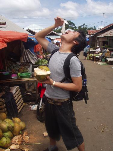 Eating Young Coconut - I was in the traditional market in Tomohon. With me were Patric and Jenifer and Catherine. They were tourist from Australia. I accompanied them to travel around Tomohon, my town. So here we were, they asked me to show the fruit section in that market.   We arrived there. It was going to rain. The sky was almost gray. So, we looked at some 'strange' fruit. Soursup, Snake fruit, many kinds of banana, candlenut, cassava, young coconut and so on were there. They were curious to try the young coconut. I also took one. It was so fantastic, after a long walking.