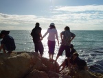 lots of people -  people gathered at a cliff near a beach