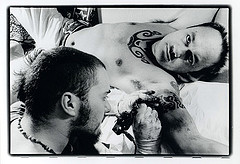 A tattoo artist working on a man - This shows a tattoo being done