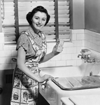 woman cleaning - wonam using baking soda to clean her kitchen sink!