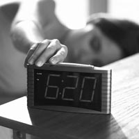 Snooze Button - A picture of a woman hitting a snooze button on her alarm clock.