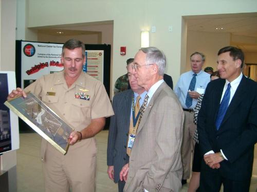 People - Orlando, Fla., Oct. 5, 2002 — Captain Andy Mohler presents a framed photograph of his command to Secretary of the Navy Gordon England during a visit to the Naval Air Systems Command's Orlando Training Systems Division. U.S. Congressman John Mica (right) also attended to tour and briefing. The Secretary was in Orlando to speak to Central Florida veterans and attend the Navy Birthday Ball. U.S. Navy photo by Capt.Kevin Wensing. Oct. 5, 2002