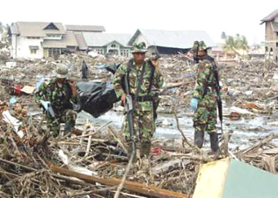 Images of Aceh 4 - Indonesian soldiers carry a body found in ruins of house in Lamteumen Timur village