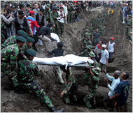 pangandaran - Soldiers lowered the body of a tsunami victim into a mass grave in Pangandaran Some 400 people were killed and 100 injured.