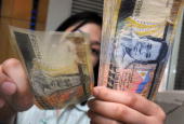 Philippine Peso - A bank teller in Manila counts 500-peso bills