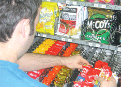 Vending Machine - Man refilling snacks vending machine - chips, chocolates and pastries.