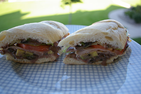 Sanwich with lots of veggies. - A sandwich with ham, cheese, lettuce tomato + more.