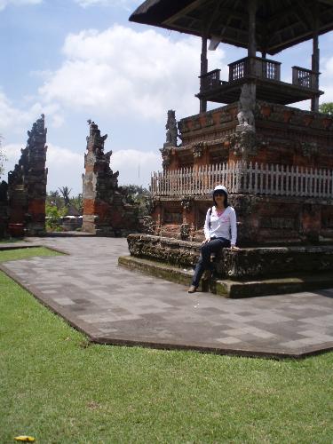 me and the pavilion - Me sitting in front of a pavilion in Bali. Other than historical value, the building shows its beautiful artistic design. The structure at the back shows the entrance gate way.