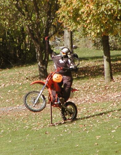 Pumpkin Biker - Halloween 2007, this pumpkin headed rider pops a wheelie under a tree. This set up was on rte 100 between Waterbury and Waitsfield