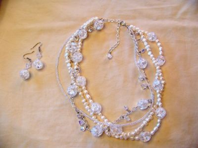 Swarovski Crystal White Bridal or Formal Necklace  - This is a beautiful custom piece in white. The necklace is four stranded. The first strand is made completely of flat sided white freshwater pearls. The second strand is made of rice freshwater pearls and large crackle glass beads. The third strand is made of clear seed beads, and the fourth strand is a sterling silver chain connected by large crackle glass beads. In between each bead are three Swarovski crystals. There are two round Swarovski crystals on either side of a bicone Swarovski crystal. The necklace is 18' long. On the end of the clasp chain is a bicone swarovski crystal. The earrings are made of a large crackle glass bead beneath a bicone Swarovski crystal. They measure 1 1/2' in length. This piece is perfect for a bride and can be made in different colors to match her bridal colors for her bridesmaids. Have unique jewelry at your wedding!!