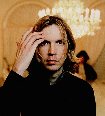 Beck - Beck CU with a chandlier in the background brushing his hair from his face