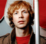 Beck - Beck CU next a subway pole wearing a red shirt and olive jacket