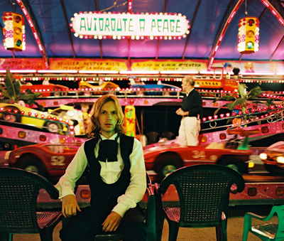 Beck - Beack seated in casino with neon lights in the back drop