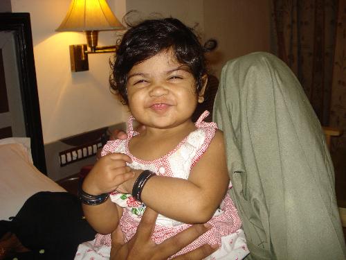 My baby - My daughter who is one year old is smiling in the snap projected here. She is exactly one year old and we are celebrating her birthday in this hotel in which this snap is taken. She is sitting on my hubby's stomach who is lying down on the bed.