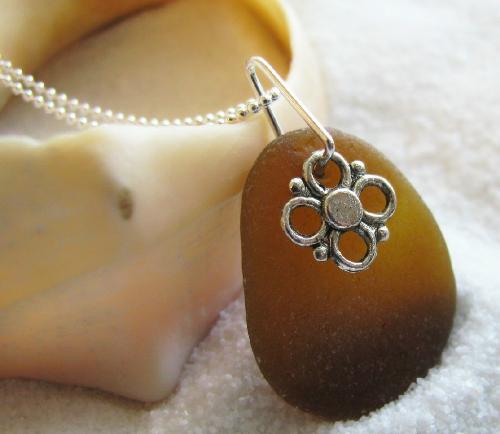 Brown Sea Glass Necklace - This gorgeous smooth piece of bottle brown sea glass measures 7/8 of an inch in length. It is a rich brown with lovely frosting from the sand and sea! This sea glass creation is accented with a small sivler flower charm, and hangs on an 18' sterling silver chain. This beautiful brown gem washed up on the beach in Hawaii. Available in my shop at Etsy.com  My sea glass creations are never altered with oils or water and appear as is. To reduce frosting, an oil, such as lavendar oil may be used to give the sea glass a more polished look.