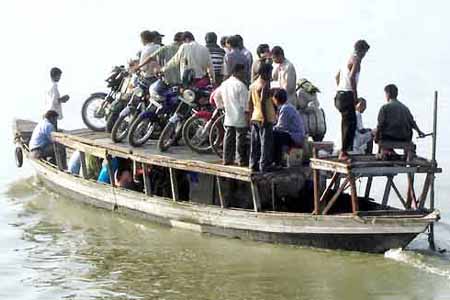 trasport - Motorbike riders along with their vehicles atop a small motorboat on the Brahmaputra taking a huge risk. This is a usual sight in some places in India.