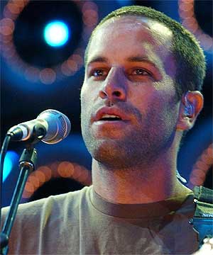 Jack Johnson - Jack Johnson singing at the mic while smiling
