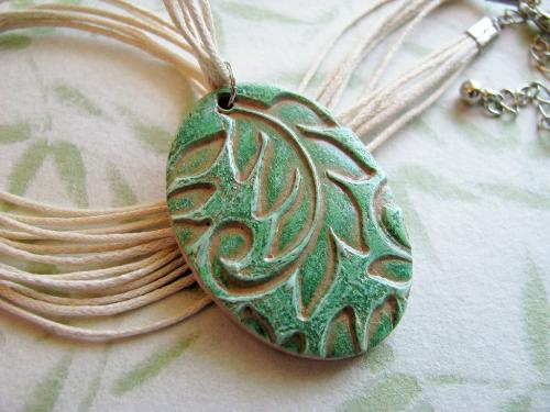 Leaves of Green Polymer Pendant Necklace  - This 1 1/2' by 1 1/8' oval pendant is made of a tan polymer clay that has been stamped with a pretty leaf print, then painted with a spring green shade of acrylic paint. The pendant was thne coated with gloss glaze for protection. This botanical pendant hangs on a 16', 6 strand linen cord with an adjustable lobster clasp (adjusts to 18')