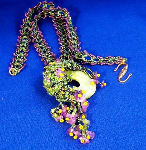 Spring Crunch Necklace - Acrylic jade colored donut embellished with seed beads and chips of amethyst and peridot. Strap in Saraguro leaf design