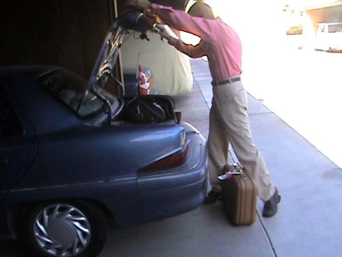 'Better Think Of Something Else...' - Here's my husband giving up on trying to get my suitcase into the trunk, and deciding that it should go somewhere else in the car.