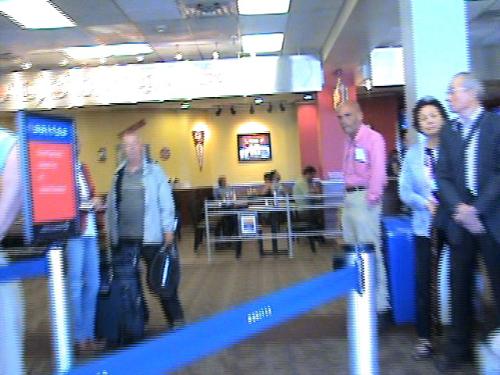 My Husband Watching Me Go.... - I hired wheelchair service, so I'm sitting in my wheelchair in line to get on the plane, with my video camera. This, and the previous shots are stills taken from the video that I made that day.