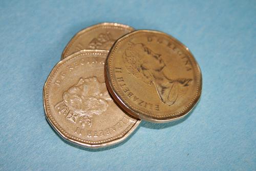 Canadian Queen Elizabeth Dollar Coins - Three dollar coins from Canada on a light blue background with an 'old world' feel, featuring the monarch, Queen Elizabeth II.