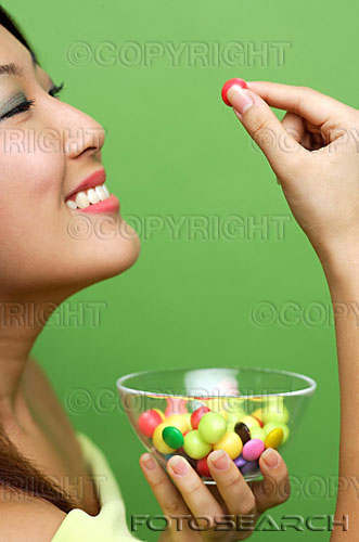candy - Woman holding single piece of candy and candy bowl.