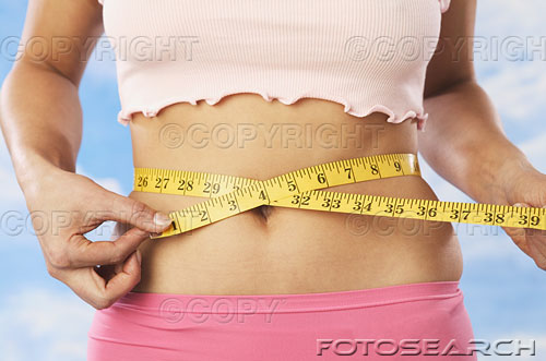 obesity - A woman measuring her waist.