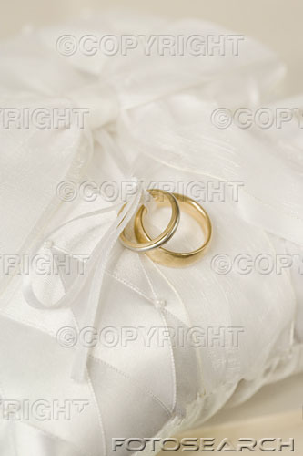 get married - Two gold wedding rings on a cushion.