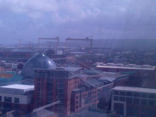 View Towards Harland and Wolffe's Shipyard - Where Titanic was Built..the 2 Gantry cranes of the yard are part of the Belfast Skyline. There's currently a 200m Ferris Wheel ('The Belfast Wheel') in the Grounds of Belfast City Hall,you can see the logo in the Titanic Memorial Picture-the Memorial is actually within the framework of the wheel at present,and the View over the Shipyard is from the top of the wheel!