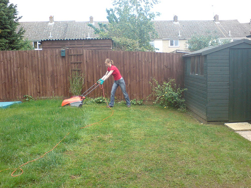 A women cutting the lawn is not unusual anymore. - This women is just about finished with her lawn cutting and it looks great. I cut my own lawn and do a great job of it also.
