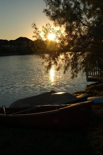 boat on beach - photo of boat with sun behind it.