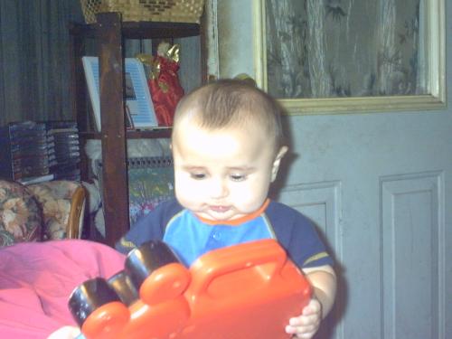 Justin taken by GG Mary - Justin sitting on Grandma Angel's Lap playing with the mickey mouse toy