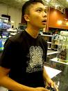 earth to.....come back to reality - Picture of a young asian adult with black t-shirt and short cut looking up at a video game with control in his hands and his mouth hanging open
