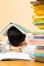 not where i want it to go - Picture of a child in school uniform asleep at a table with books stacked high in front of him and a book over his head with his homework waiting