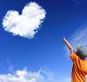 It never stops speaking to you - A picture of a boy in orange t-shirt and hat pointing up to the beautiful deep blue sky with a cloud in the shape of a heart