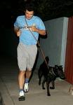 does it work for you? - Picture of a man jogging in light blue tshirt and khaki shorts with black dog on leash all at night