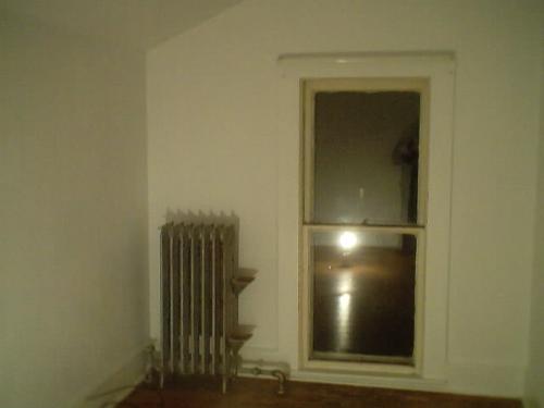 old radiator still in use, floor to ceiling window - upstairs single bedroom apartment flat, in old home, unique radiator, backwards L shaped living room on top floor of old house with plaster walls, lathe for interior of walls, lead in the paint, built beginning of 1888.