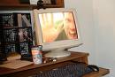 Happy MyLotting!!! - A desktop computer sitting on a desk with papers and can next to it, on the monitor is a full screen closeup of a guy waving from monitor