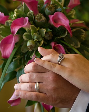 Wedding rings and bouquet - A photo of a pink wedding bouquet and wedding rings on the newly married couple's hands.