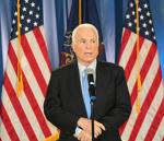 no questions please - Picture of McCain on stage, in black suit, in front of two big American flags looking serious but unsure no questions please - Picture of McCain on stage, in black suit, in front of two big American flags looking serious but unsure