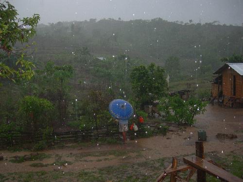 it's raining - It's raining heavily and a woman fetches water in the only available faucet in the community. Rain does not deter her from doing important house chore.