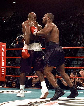 Fighting In The Ring - Mike Tyson and another boxer in the ring. The boxer has his back to Mike Tyson and Tyson is tapping him in the back.