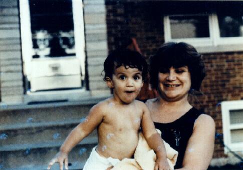 Ghost In The Door - In the picture, a mother and her son are outside. If you look behind them, you can see what appears to be an elderly lady's face in the doorway!