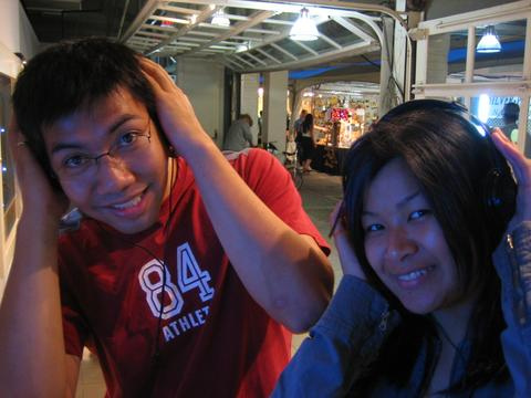 Listening to music while posing. - Two Asians listening to music while they're on a wet market.