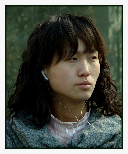 Chinese Sound Trip - An Asian (Chinese) girl is pondering about something while listening to her music. Very nice photograph.