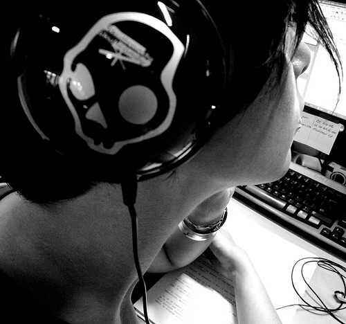 Skully Headphone - A nice photograph of a teenager listening through a headphone while surfing the net.