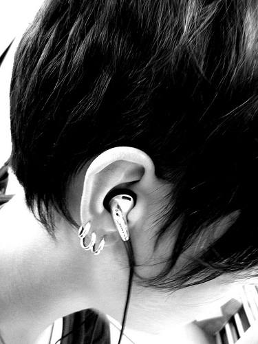 The Girl with Three Earrings - A black and white photo showing a girl with three earrings, listening to music.